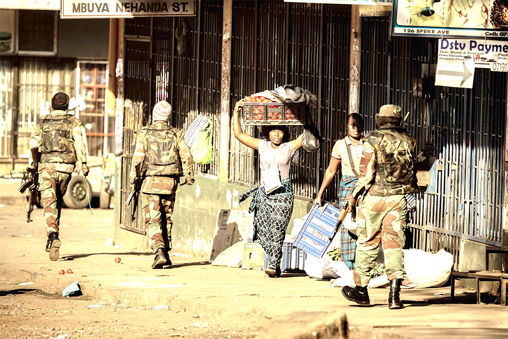 A vendor scurries for cover with her wares as soldiers disperse demonstrators