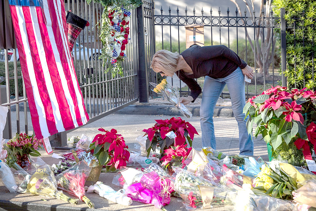 A mourner leaves flowers at a makeshift memorial in tribute to former US President George H. W. Bush outside a gated community where Bush lived in Houston, Texas, on December 2, 2018.