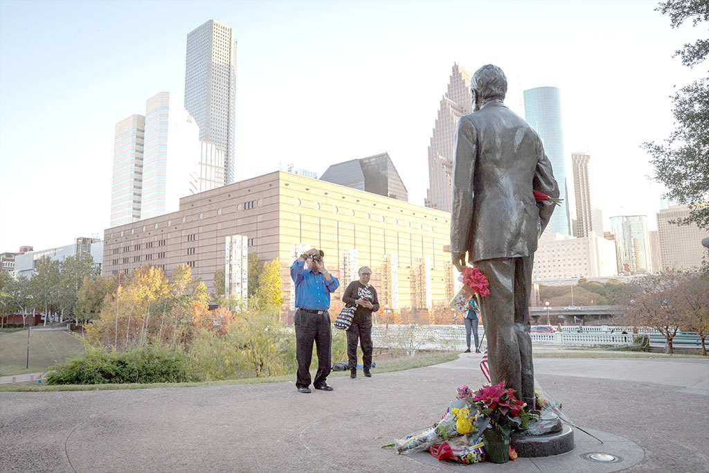 A man photographs a makeshift memorial in tribute to former US President George H. W. Bush at a monument in his honor in Houston, Texas, on December 2, 2018.