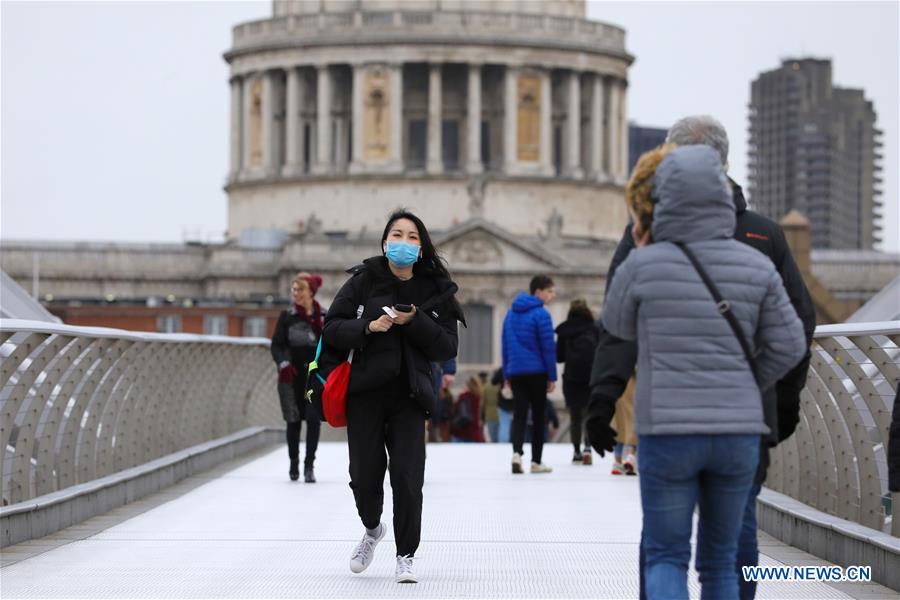 A person wearing a mask walks across the Millennium Bridge in London, Britain, on March 9, 2020. (Photo by Tim Ireland/Xinhua)