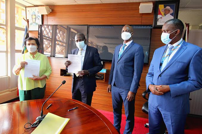 Finance minister Matia Kasaija (2nd left) exchanges documents with Ms Enrica Pinetti (right) after signing an agreement with the Finance ministry to establish a coffee processing plant in Uganda, on February 10, 2022. PHOTO/COURTESY