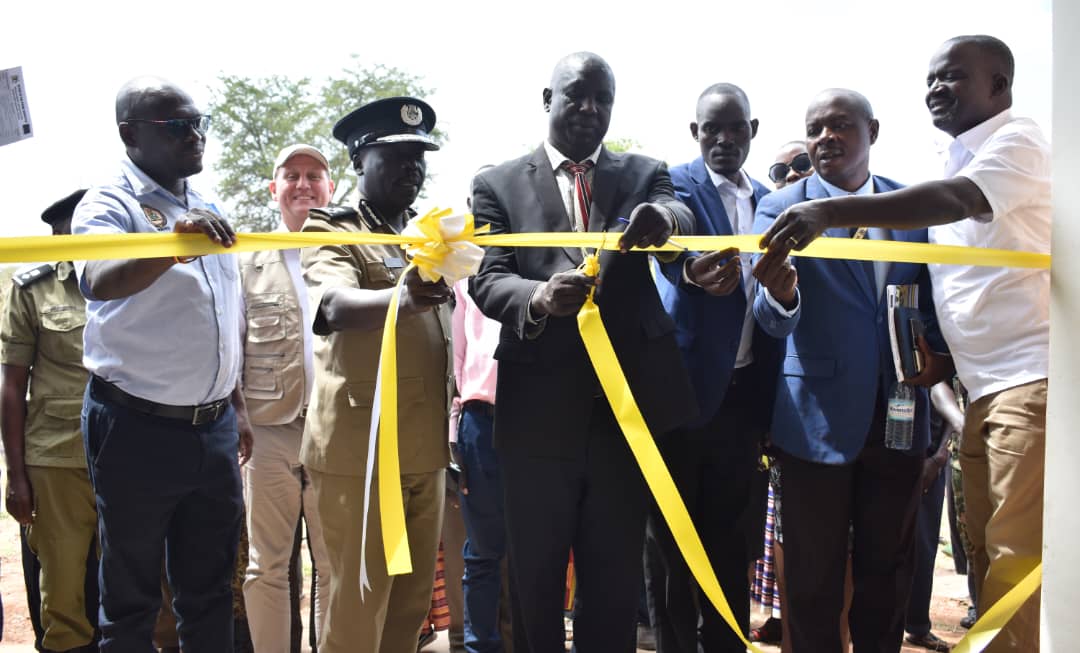 John Bosco Okello, the Abim LC5 chairperson flanked by AIGP Ocaya James, director research, planning and Development at the Uganda Police Force, Mr Gonzaga Mayanja, the Commissioner Monitoring, and Evaluation, Local Governments at OPM, cuts a ribbon to launch the Morulem Community Police Post on November 29, 2022.