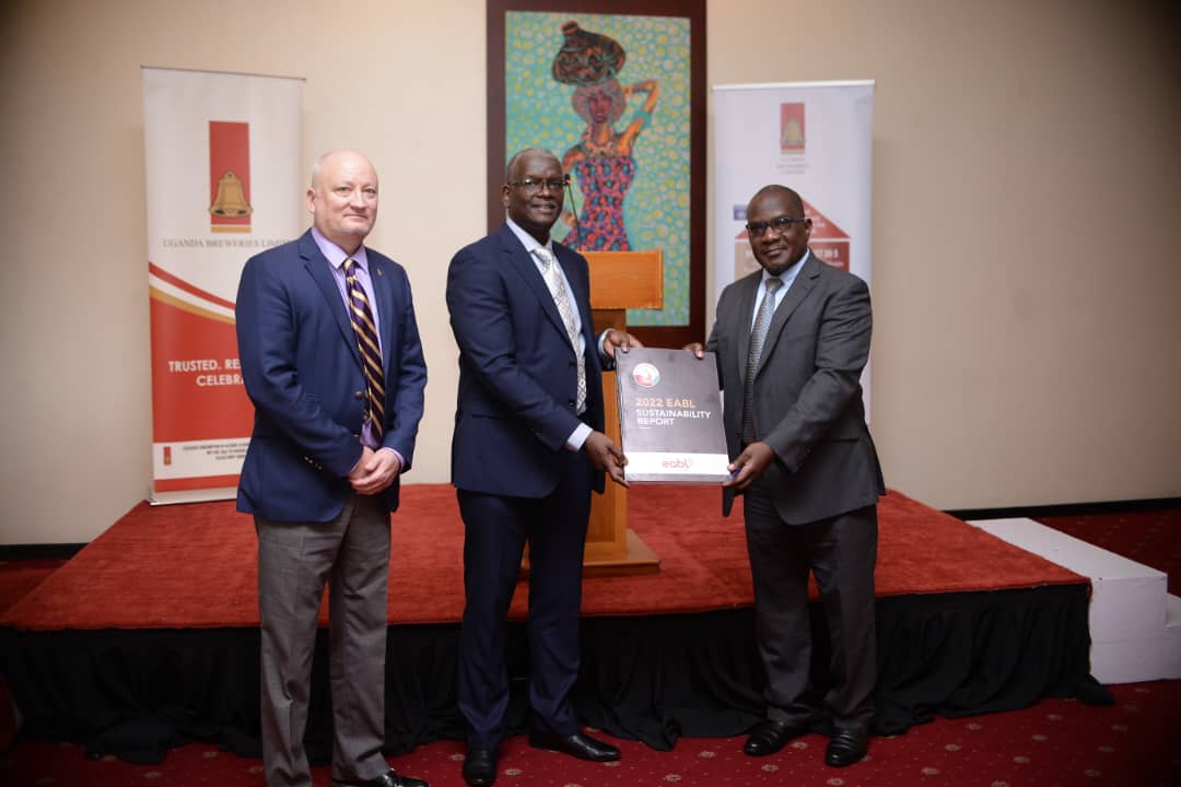 Andrew Kilonzo - UBL MD (center) hands a copy of the Sustainability Report to Eng. David Luyimbazi as Damon Ansell - Diageo Africa Corporate Relations Director looks on