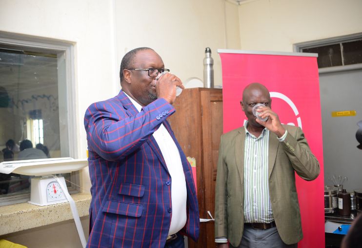 Absa MD - Mumba Kalifungwa, and Fort Portal RRH Deputy Director - Dr Oscar Kaliisa taste the water from one of the dispensers