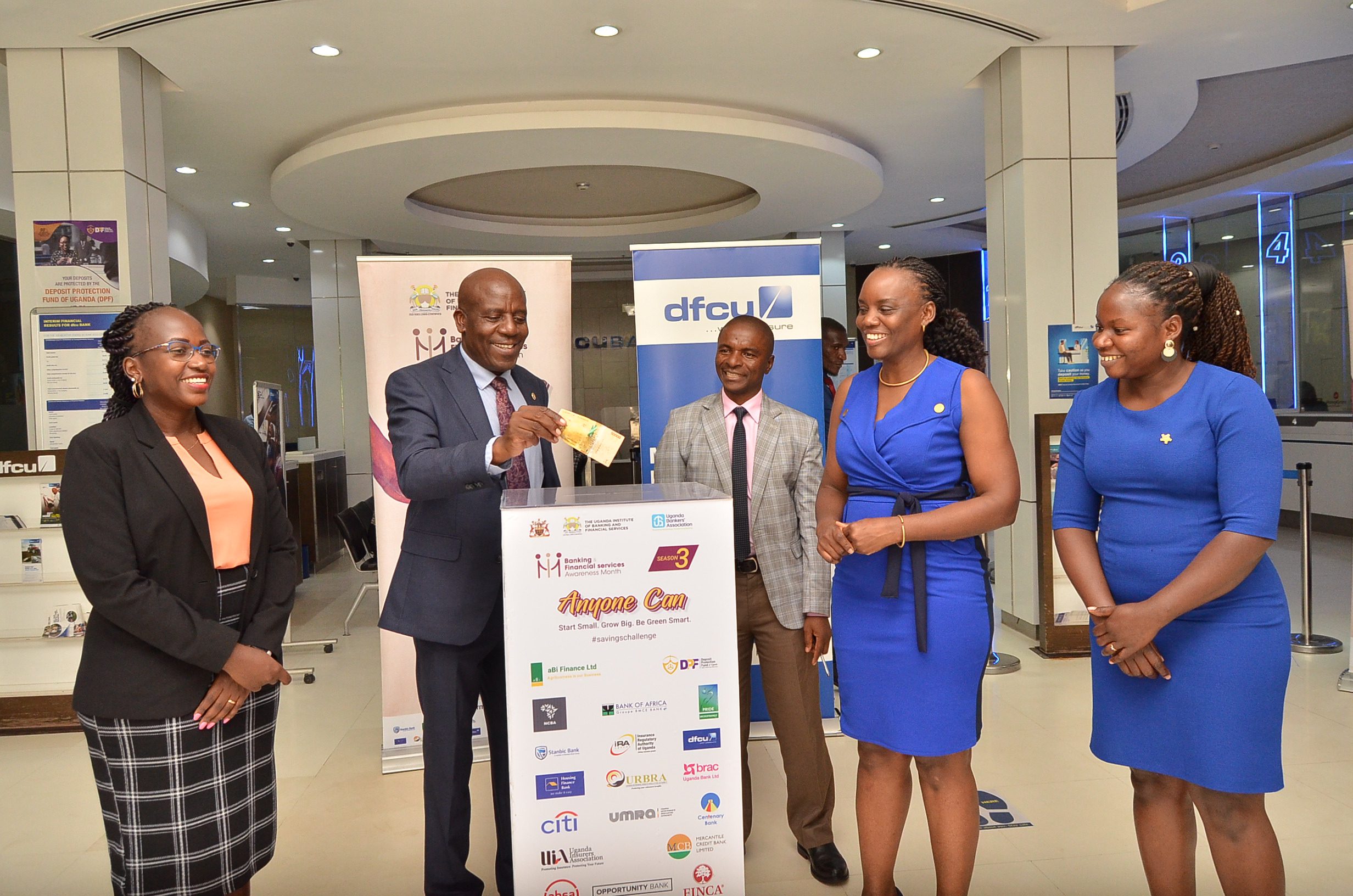  dfcu Bank's CEO Charles M. Mudiwa (2nd left) makes a contribution to the ‘Giant Savings Box' to mark the commencement of dfcu Banks’ participation in the “2023 Savings Challenge” campaign at the bank’s head offices on Kyadondo road, Nakasero.