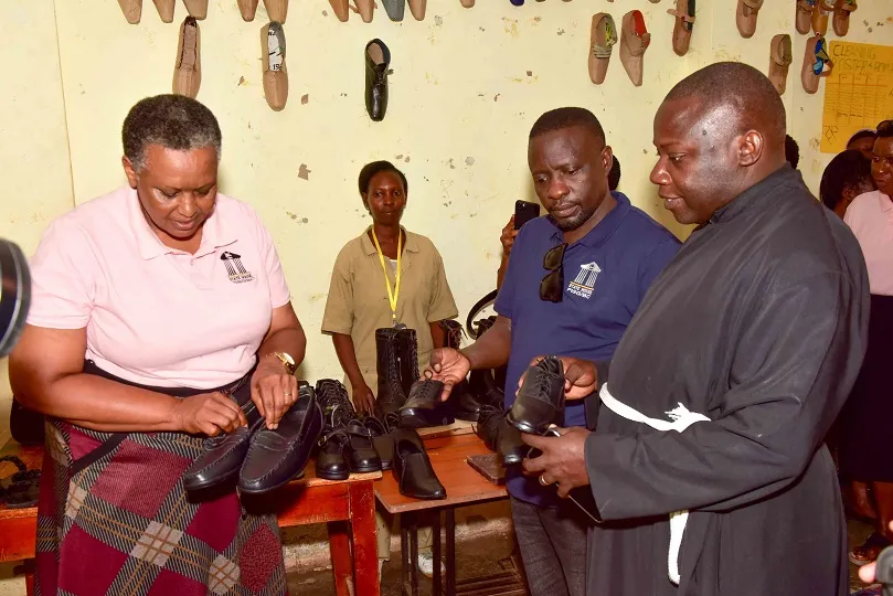 left-right) Presidential Initiative on skilling the Girl/Boy Child (PISGC) head of the project Faith Katana Mirembe, PISGC manager Hillary Musoke Kisanja and All Saits Church Rev. Stephen Lumu admiring shoes made by Students of PISGC at Mutundwe centre this was during the Presidential Initiative on skilling the Girl/Boy Child project 7th intake inspection of the skills of the students as they show case their work at Mutundwe centre on 17th February 2023. Photo by PPU/Tony Rujuta.