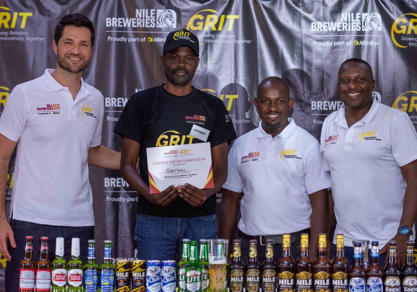 Adu Rando (L) the Managing Director Nile Breweries (NBL), Emmanuel Njuki, head NBL Head of Legal and Corporate Affairs (2R) pose for a photo after handing over a certificate to one of the participants during the training.