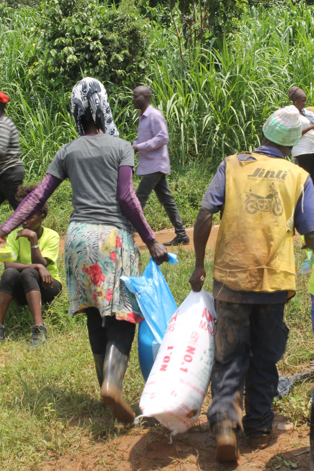 Beneficiaries of Kiteezi Samaritan's support make their way home, carrying essential items such as food and household supplies, after receiving aid following the Kiteezi landfill landslide. The distribution brought hope and comfort to many affected families in the community.